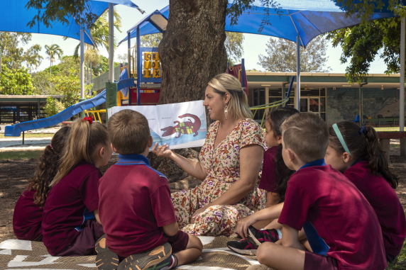 Alisha reading with children under a tree 