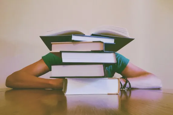 Student slouched behind a pile of books