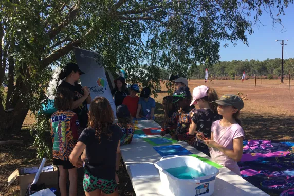 children and Carla standing around table under tree