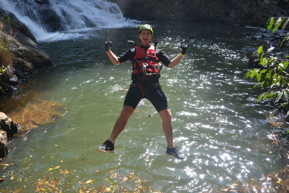 Joel jumping into a lake at the bottom of a waterfall