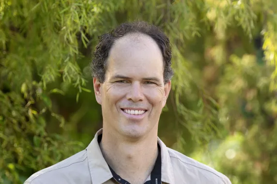 Sam Banks, head and shoulders, with green vegetation behind 