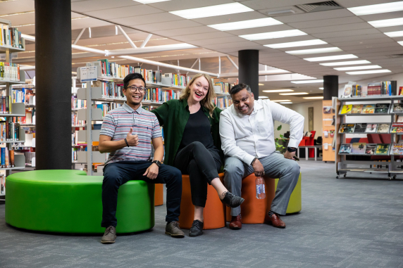 three students sitting on chairs inside the CDU Alice Springs campus library