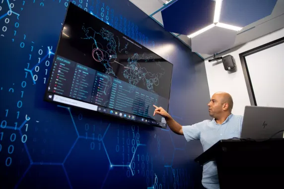 man points to large screen