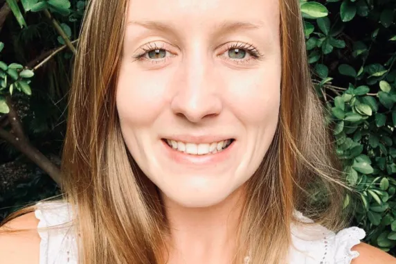 Staff portrait of Hayley Geyle young women with light brown hair smiling in front of trees