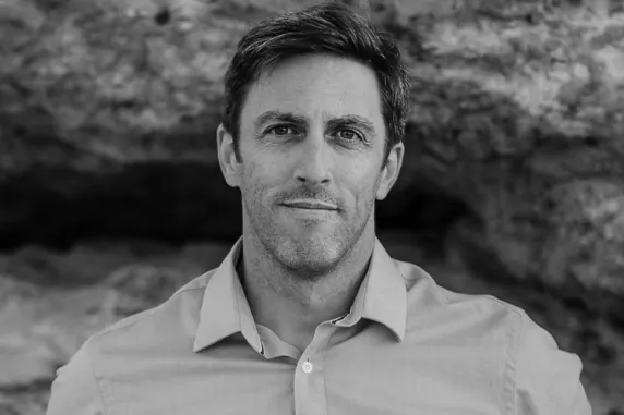 Author Russell Marks against rockface in black and white