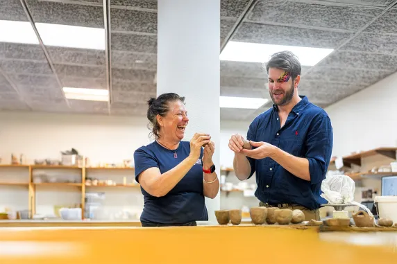 Two people making pots from clay