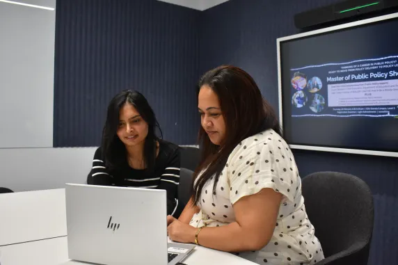two students looking at a laptop talking