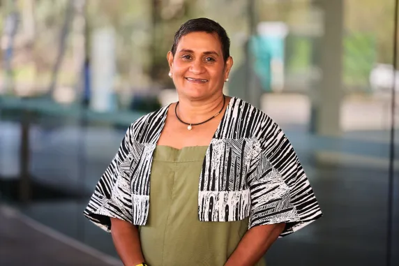 smiling yvette with green linen and cropped jacket in front of waterfront campus