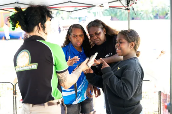 3 students looking at a baby croc