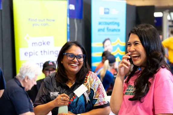 2 women laughing front of a information stall