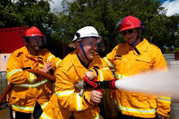 3 guys in firefighting gear using hose