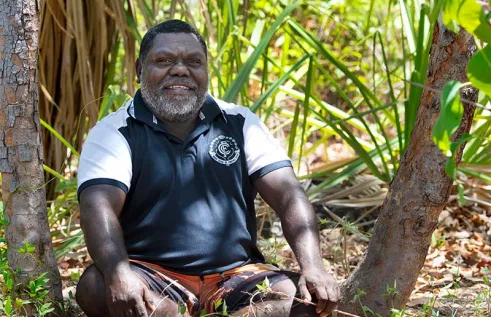 Stephen Dhamarrandji pictured sitting among native bush lands.