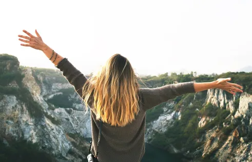 A photo of the back of a girl with her hands in the air in celebration