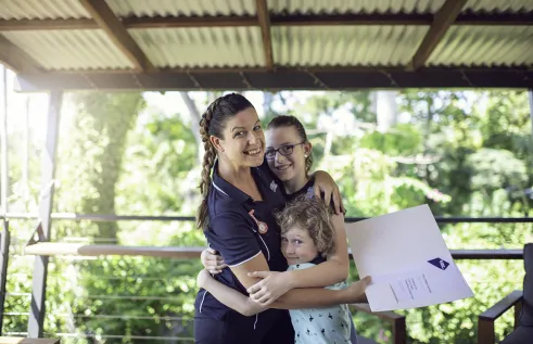 Mum hugging her children with a graduation certificate in hand