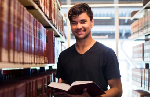 Mark in the library holding a book