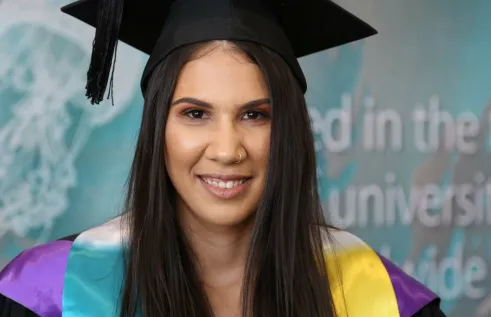 Rikki in her graduation gown and cap smiling