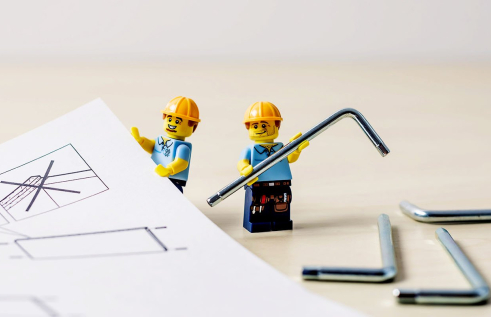 Lego engineers standing among engineering plans