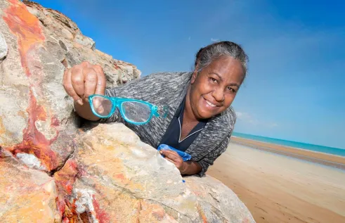 Indigenous lady sitting on a rock and smiling