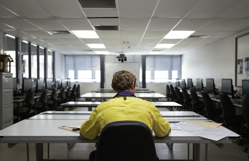 Male student wearing high-vis clothing sitting at a desk in a classroom