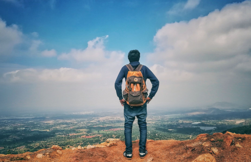 Male traveller with backpack overlooking a mountain view