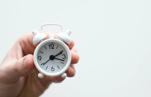Hand holding clock to represent time management