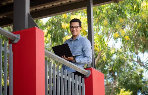 Student smiling while holding a laptop
