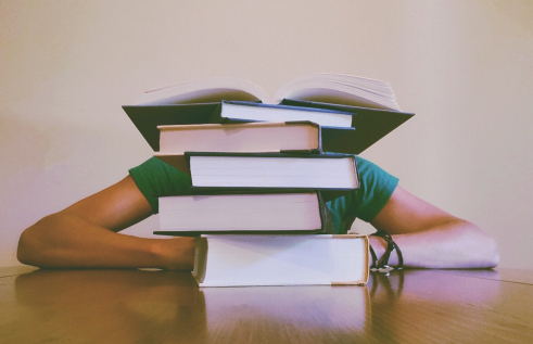 Student slouched behind a pile of books