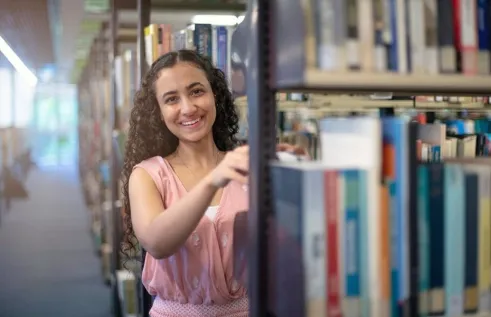 CDU student Nancy Soliman in the library choosing a book.