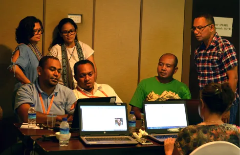 A group of people sit around a set of computers