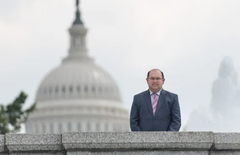 Emre smiling in front of a view of the White House