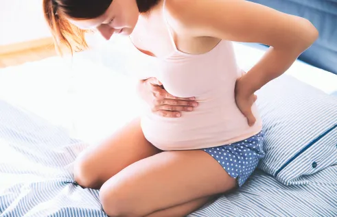 A pregnant woman on a bed with back pain