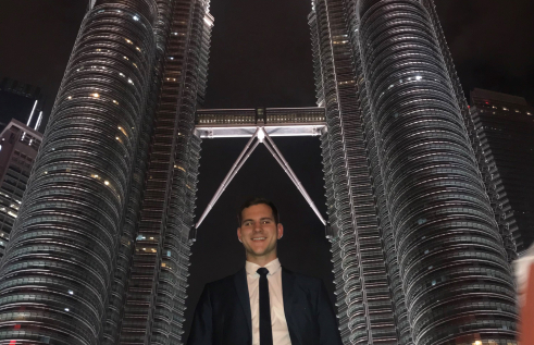 Joel smiling in front of the Petronas Towers in Kuala Lumpur, Malaysia