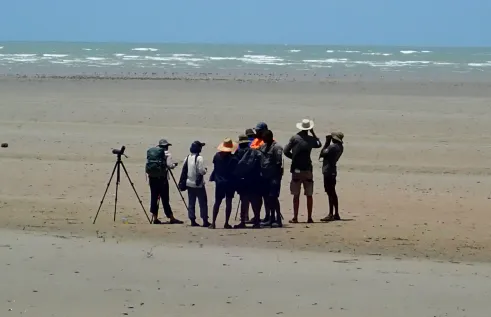 a group of people on a beach with the ocean in the distance