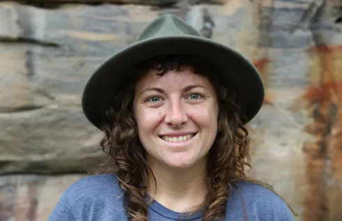 Jennifer Macdonald head and shoulders, wearing hat, with stone wall in background