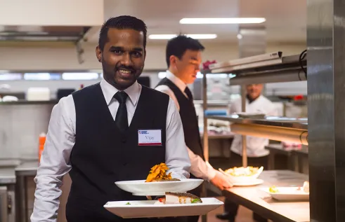 Student in training with a plate of food at Karawa Training Restaurant in Palmerston 