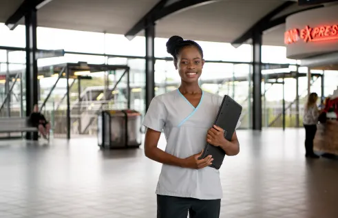 CDU nursing student Fifi Giraneza holding her laptop in a train station