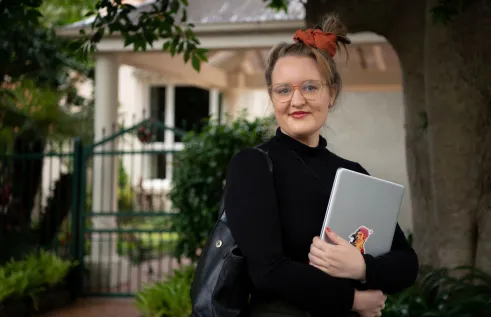 CDU student Claire Bowditch with laptop in front of her home