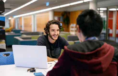 CDU student Nicholas in the library with a study buddy