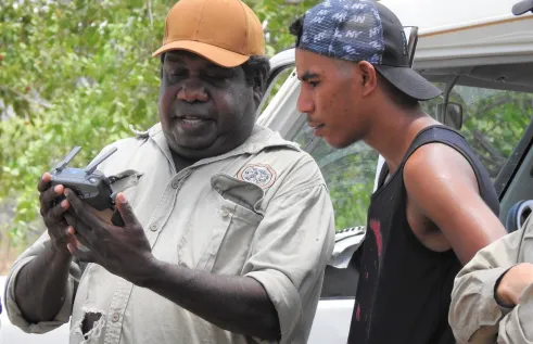 Traditional Owner Ryan Barrowei teaches his cousin Mark Hunter how to use the drone to see Country after cool fire management at Jarrangbarnmi.