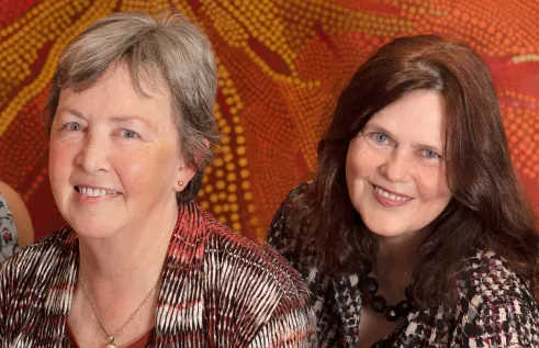 Gill Westhrop & Emma Williams against orange Indigenous painting by Linda Ford