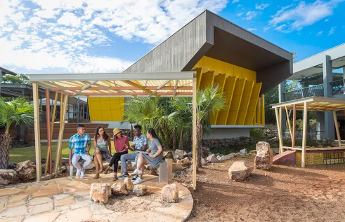 a group of students sitting and a bench at casuarina campus