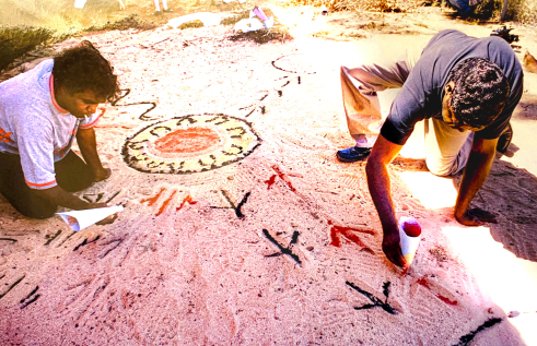 men drawing animal tracks in sand