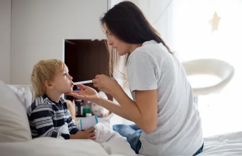 Mother giving medication to sick child