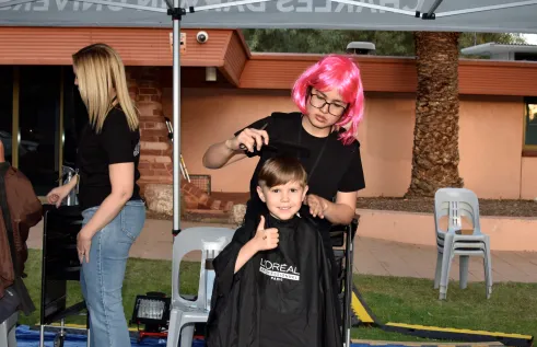 child getting hair cut gives thumbs up