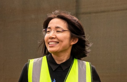 Dr Jady Li, head and shoulders, wearing hi-vis vest, with brown background