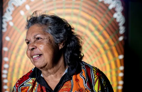 First Nations women smiling in front of Indigenous Art