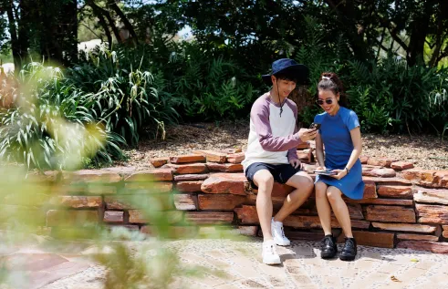 Students scrolling through mobile phone under tree