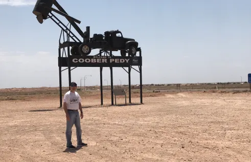 man stands in front of sign in outback