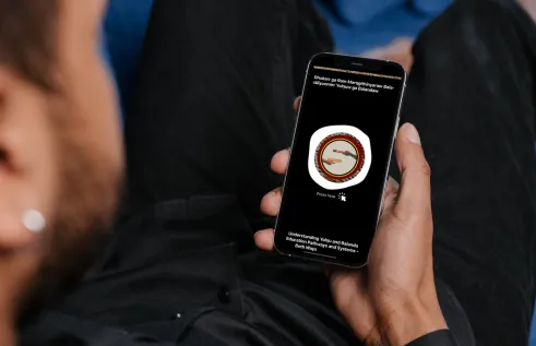 A young Indigenous Australian man looks at the Yolŋu Healthcare App on his phone