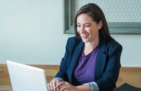 Professional woman with dark brown hair working remotely on laptop